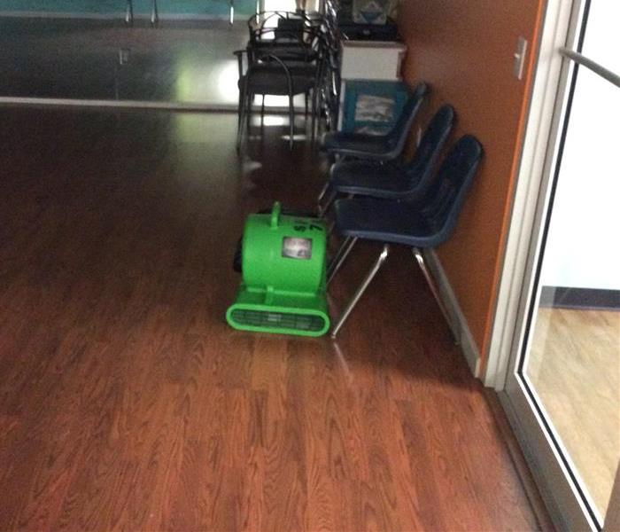 Green air mover next to blue chairs in an office
