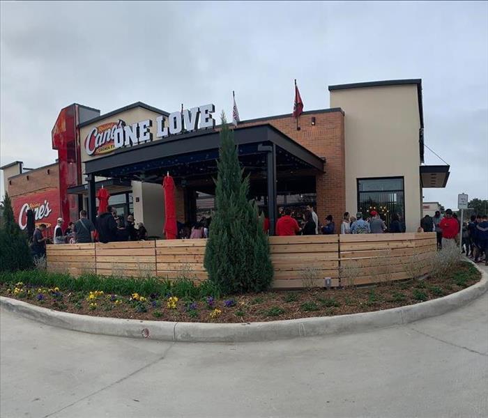 customers lined up outside a crowded patio at a Raising Cane's chicken restaurant
