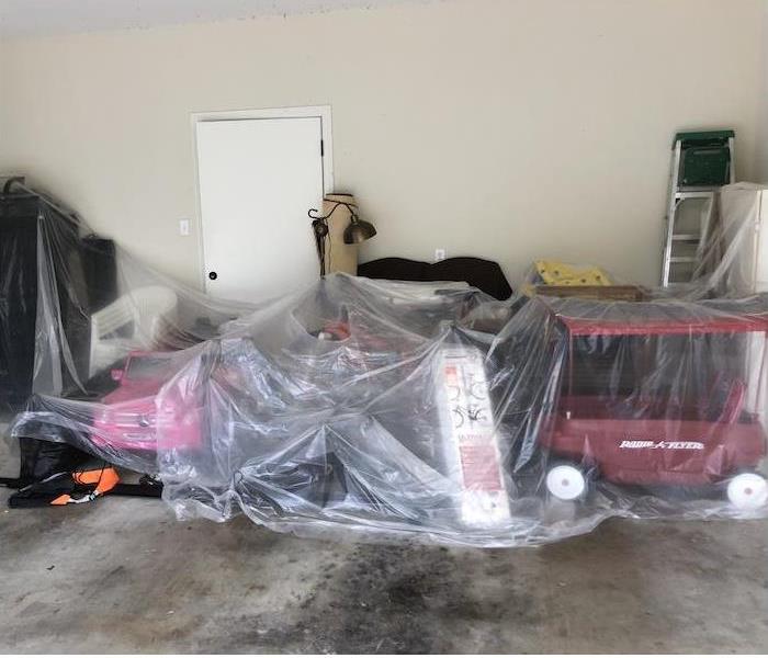 Toys and items covered under poly sheeting in a garage