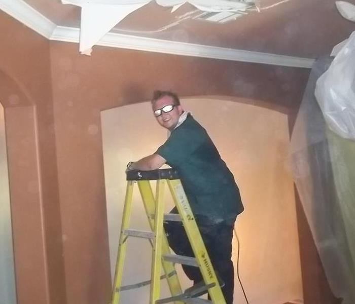 Man on ladder with sunglasses in a room