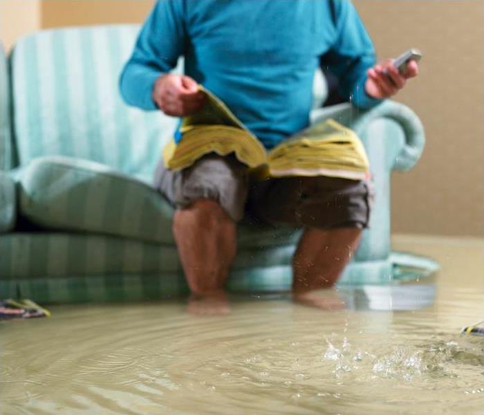 flooded living room with man sitting on a couch