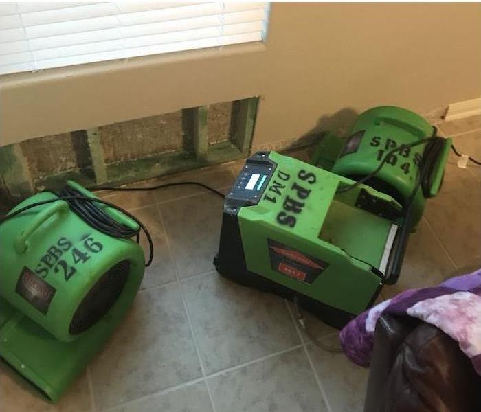 Cut drywall with SERVPRO equipment on the floor of a home drying the open area on the wall. 