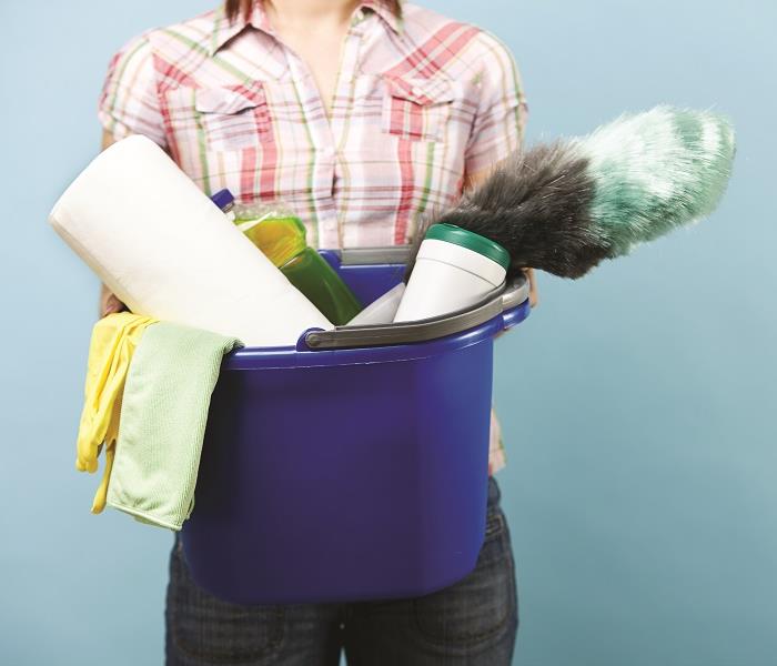Woman holding mop container full of cleaning supplies
