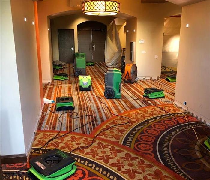 A hotel hallway with SERVPRO equipment on the floor. 