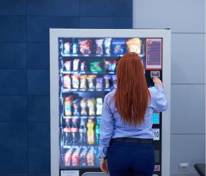 Woman with red hair standing in front of vending machine