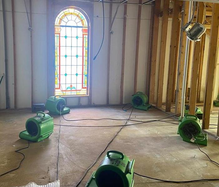 A room with a stained glass window has had its walls removed and 5 SERVPRO green air movers strategically placed throughout