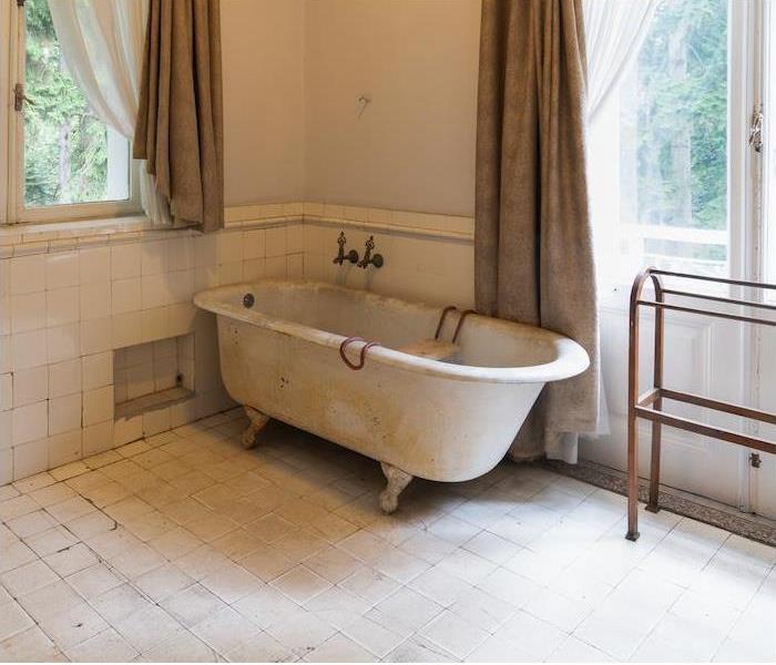 bathroom with older style tub with mold and mildew covering the tile floor and tub
