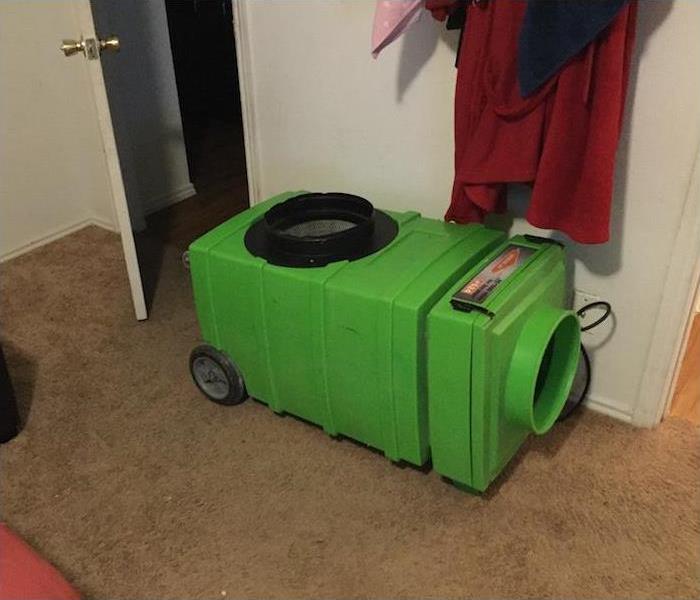 Green air scrubber on brown carpet in a room in a house